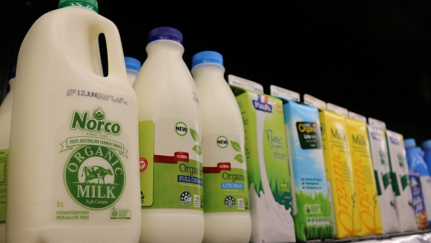 Bottles and cartons of organic milk in a supermarket fridge.