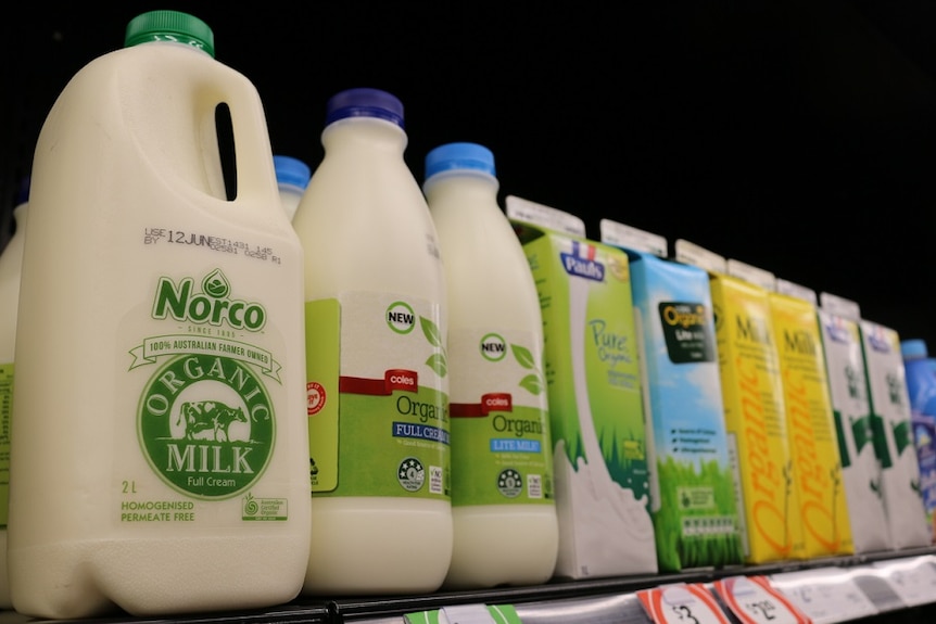 Bottles and cartons of organic milk in a supermarket fridge.