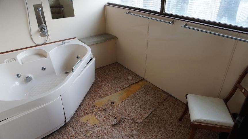A spa bath in a bathroom where the tiles have been pulled up. 