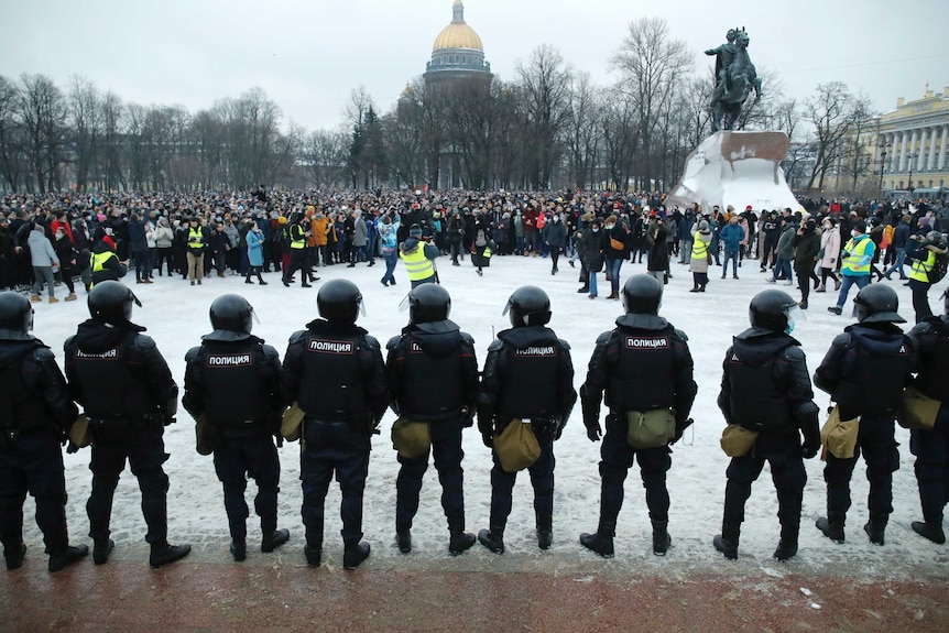 Police form a line several metres away from a large gathering of protesters in snowy St Petersburg.