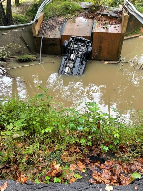 A car upside down in water off a collapsed bridge 