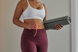Woman holds yoga mat and pelvic floor exercise device for a story on pelvic floor devices