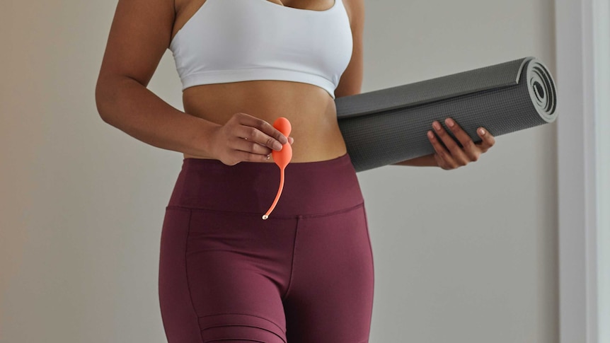 Woman holds yoga mat and pelvic floor exercise device for a story on pelvic floor devices