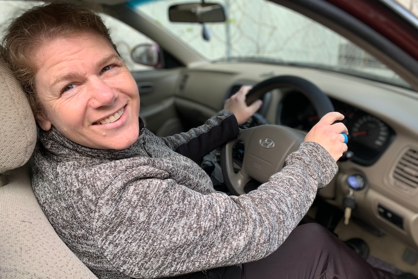 A woman smiling at the wheel of her vehicle 