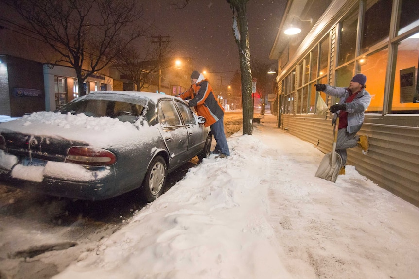 Men clear snow from car in New Haven, Connecticut