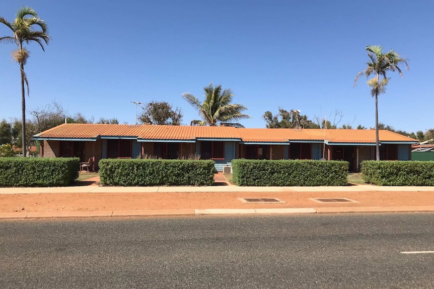 A long, flat, one-storey building with four neatly-trimmed hedges out the front.