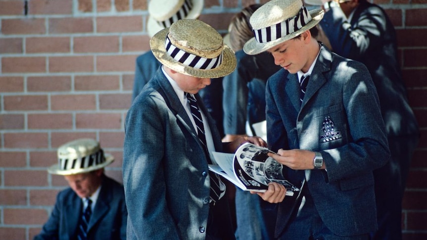 School boys in hats and blazers gathered in yard