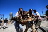 Medics carry a wounded defected soldier after clashes with police in Sanaa