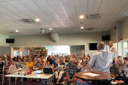 A group of people, some with hands raised, in an audience