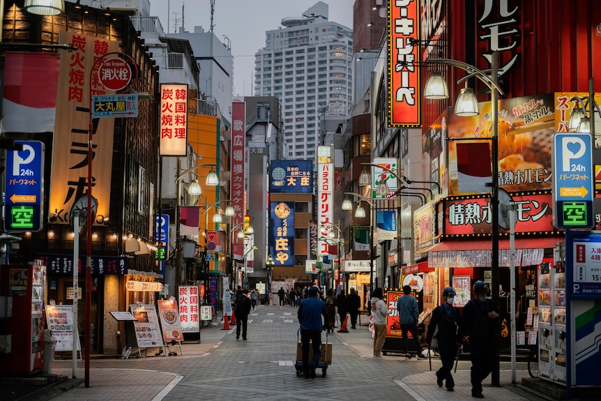 Улица в Японии, по которой ходят люди и много вывесок магазинов.