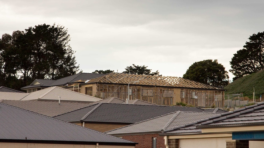 Roofs of several houses, house under construction in background.