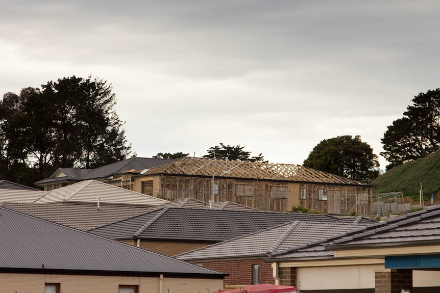 Roofs of several houses, house under construction in background.