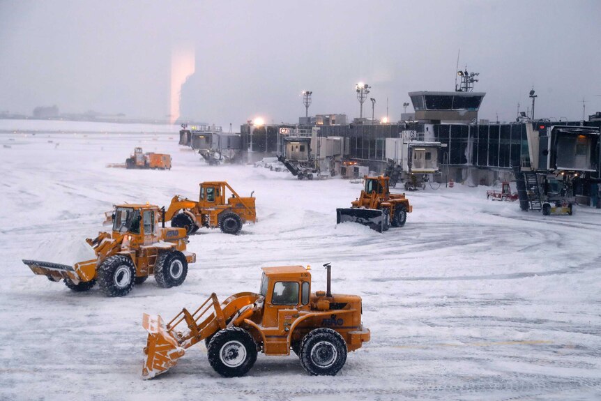 Front-loaders clear snow from the area at LaGuardia Airport.