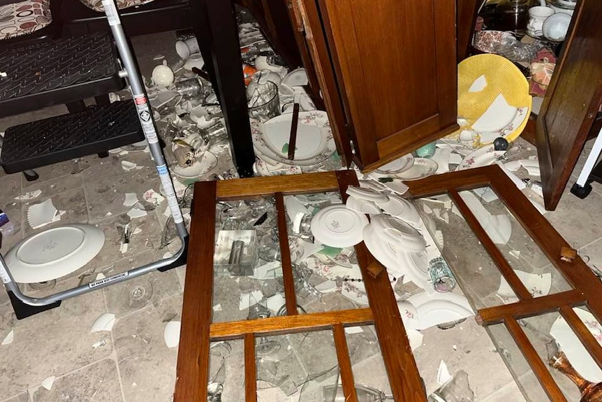 A shattered cabinet with shattered plates on the ground