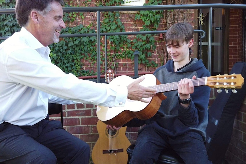 A new guitar is handed to Tom by his music teacher Steve Allen.