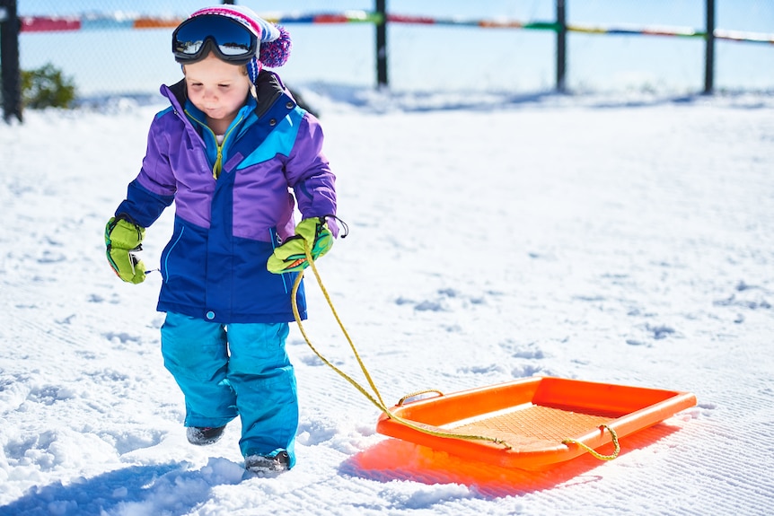 A girl pulling a toboggan across the snow