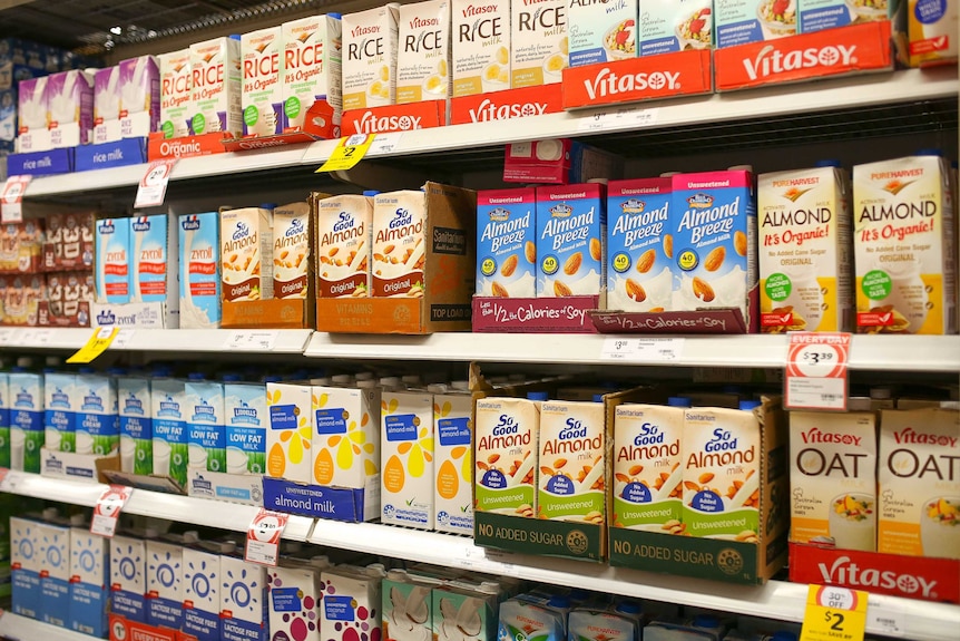 Supermarket shelf of rice, soy and almond milk boxes.