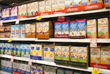 Supermarket shelf of rice, soy and almond milk boxes.