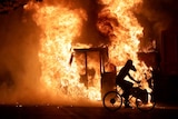 A man on a bike rides past a city truck on fire outside the Kenosha County Courthouse in Kenosha, Wisconsin.