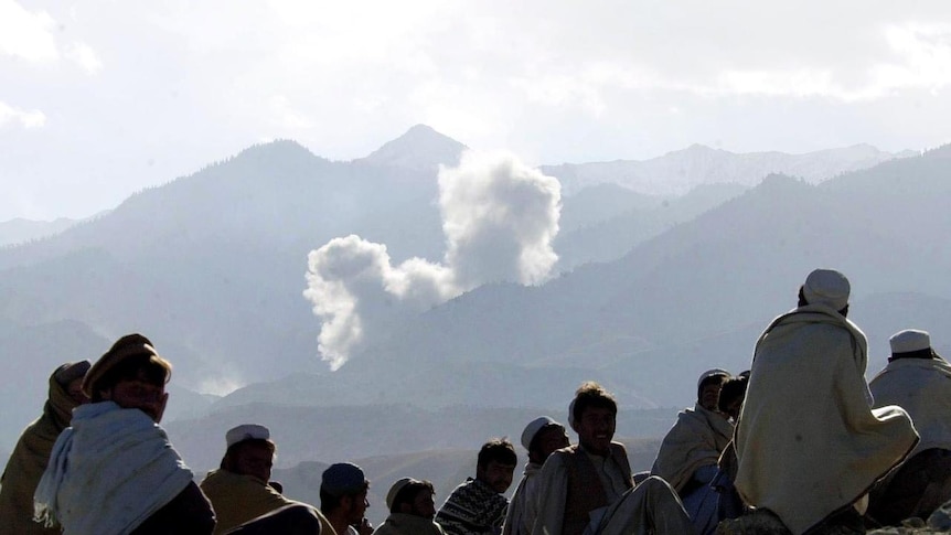 Afghan villagers watch as smoke from bombs dropped by US B-52 planes rises from al-Qaeda positions