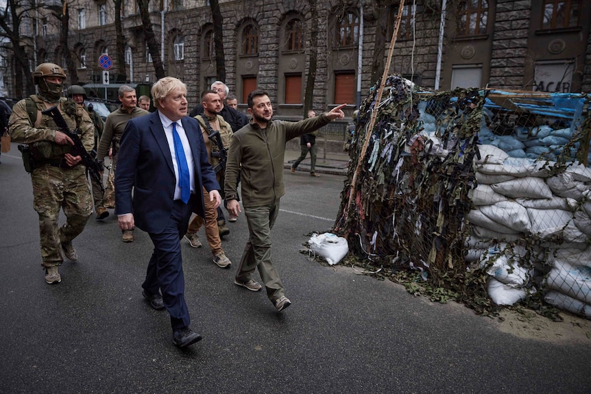 Boris Johnson and President Volodymyr Zelenskyy walk past a bunker.