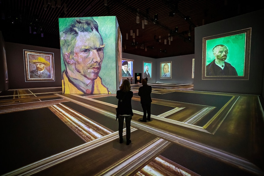 People stand in a gallery space displaying Van Gogh self portraits