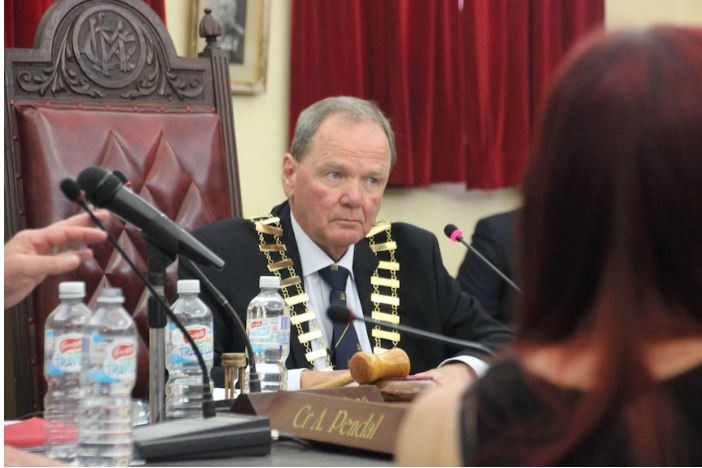 A man sitting in a chair with mayoral chain of office.