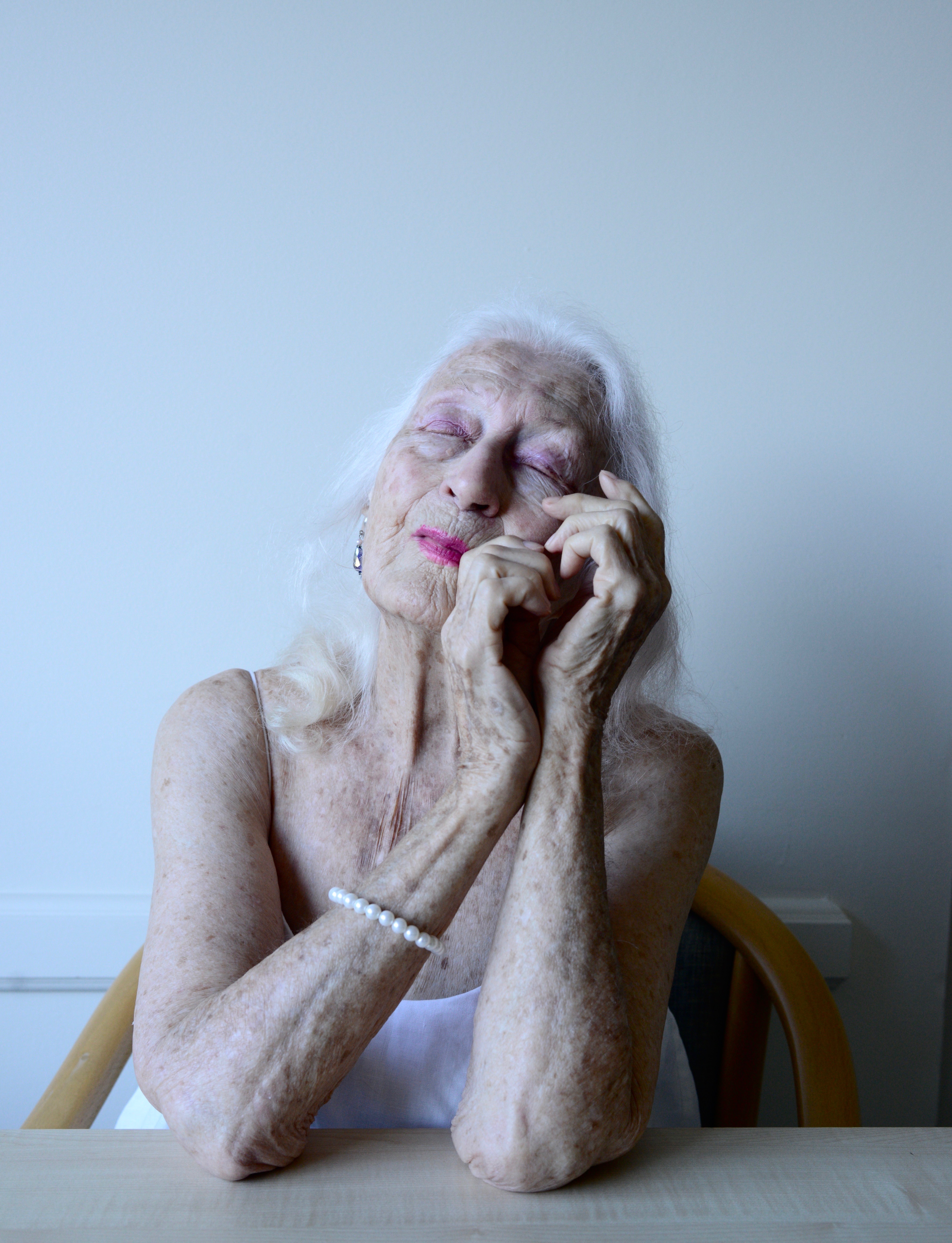 An older woman closes her eyes, looking wistful.