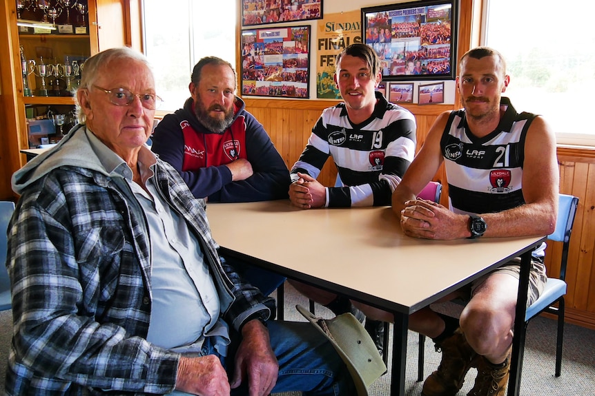 Un homme âgé est assis avec trois autres hommes