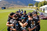 The White Ferns huddle with a mountain range in the background in Queenstown