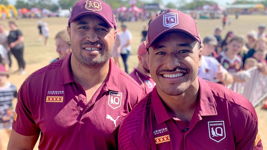 Two men wearing Queensland Maroons rugby league uniforms.