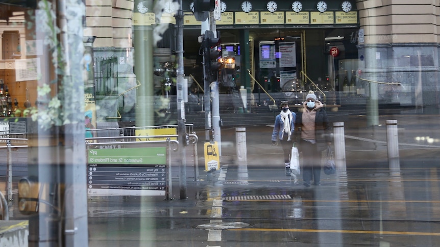 下雨天，人们在弗林德斯街站外的窗户外行走。