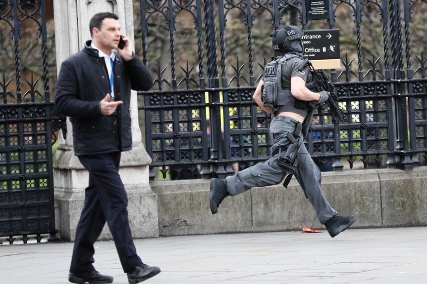 A heavily armed policeman runs across Westminster Bridge.