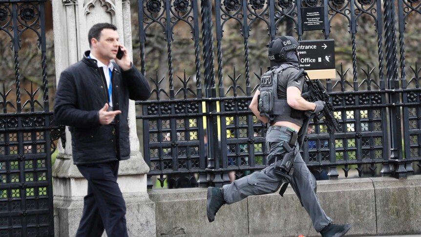 A heavily armed policeman runs across Westminster Bridge.