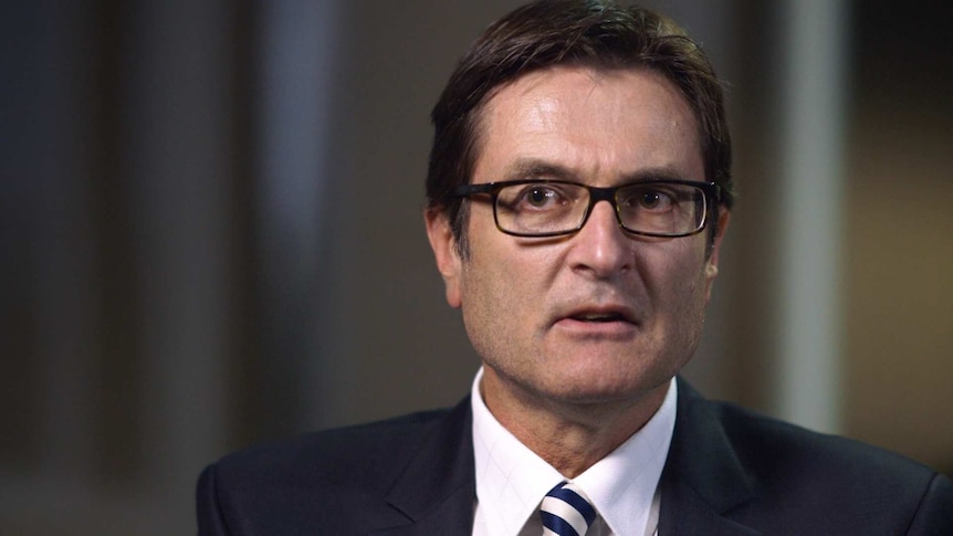 A man with short brown hair and glasses wearing a suit