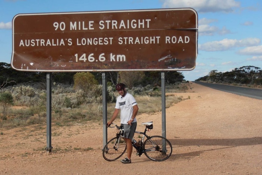 Matt Napier sitting on a bike in front of a street sign in Australia.