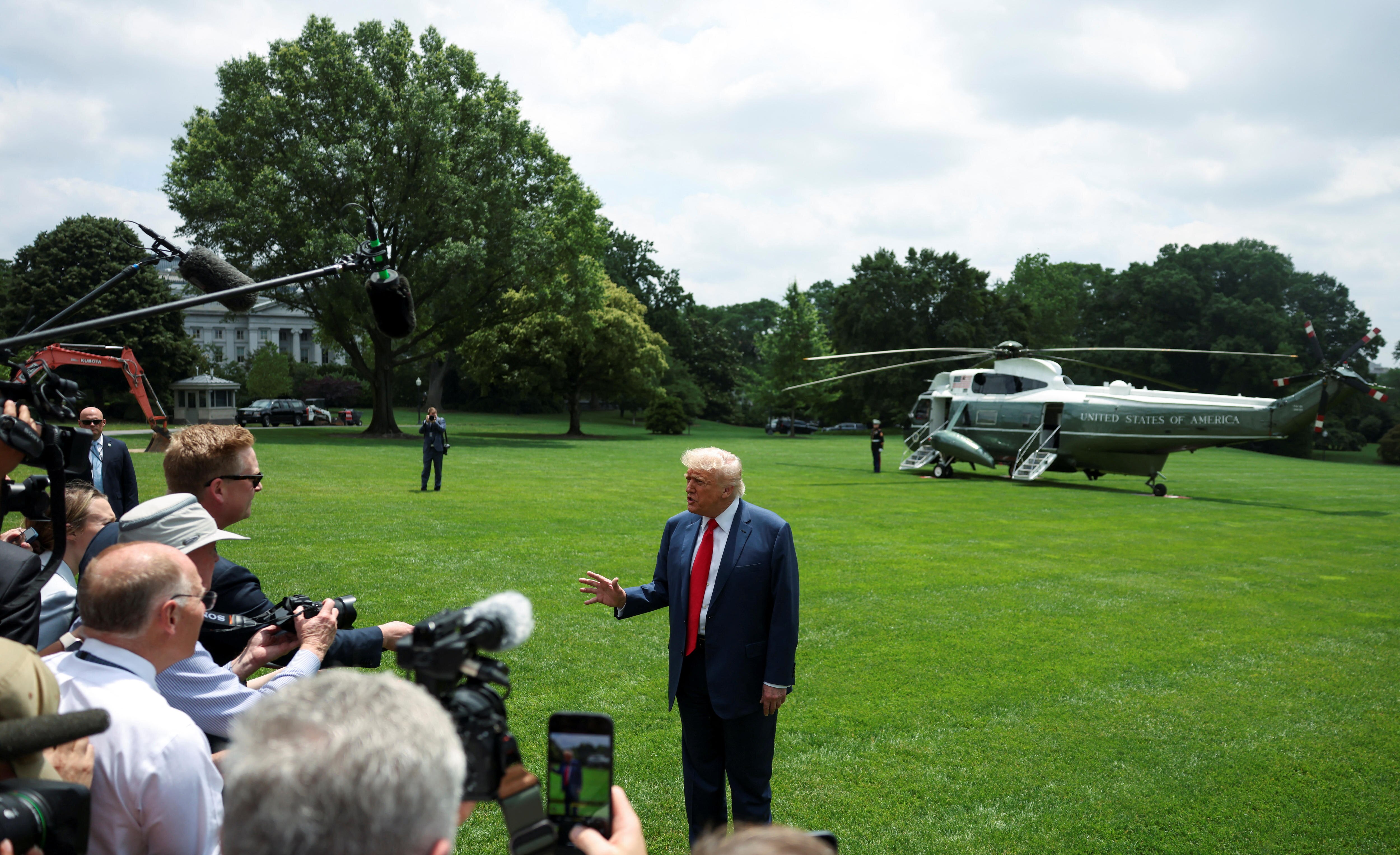 The president speaks to a crowd of reporters as he stands on the lawn 
