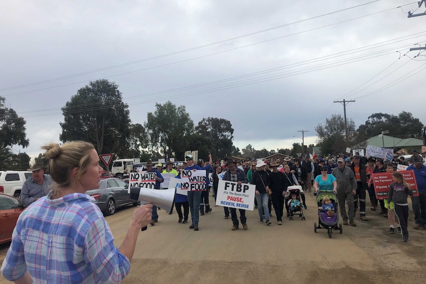 a crowd of people march through the town of Tocumwal holding signs