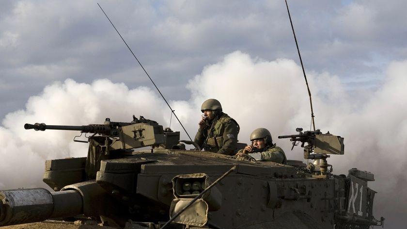 Israeli soldiers look out from atop a tank maneuvering outside the northern Gaza Strip.