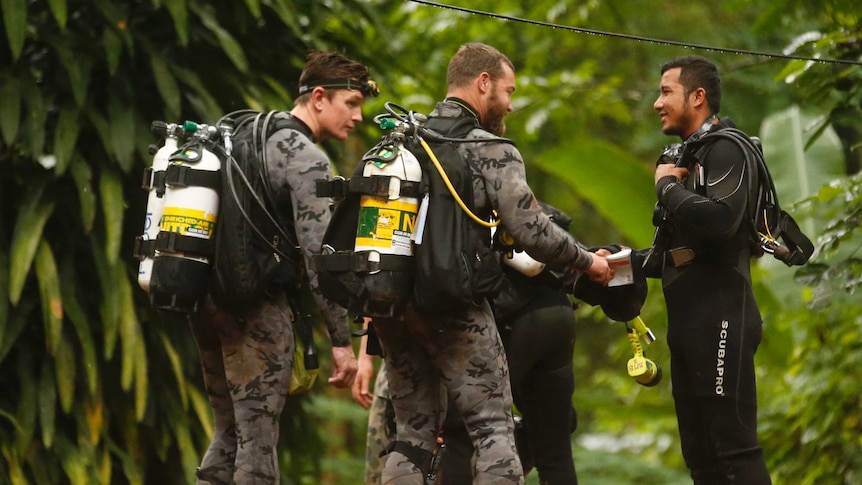 Australian Federal Police and Defense Force personnel talk to a Thai rescuer