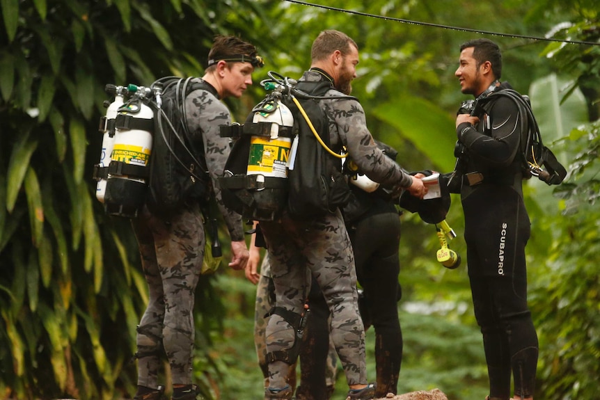 Australian Federal Police and Defense Force personnel talk to a Thai rescuer