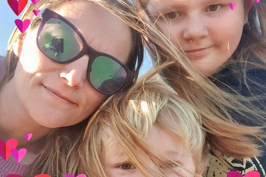 A woman and her two children huddle together for a selfie.