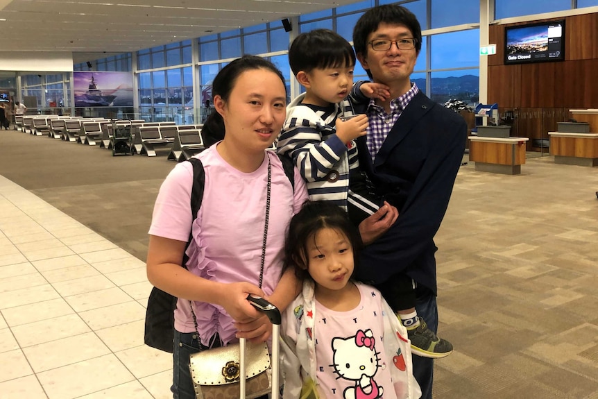 Stanley holds his little boy and their little girl leans against him and Amy.