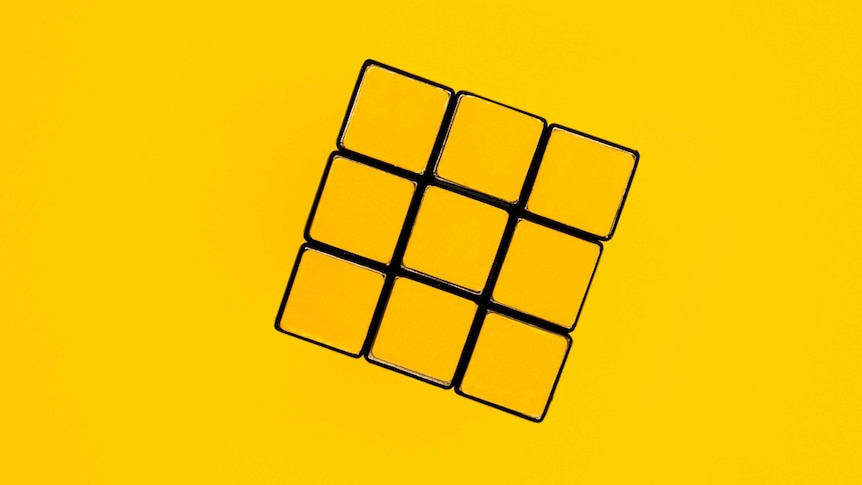 The yellow face of a solved Rubik's cube, against a yellow background