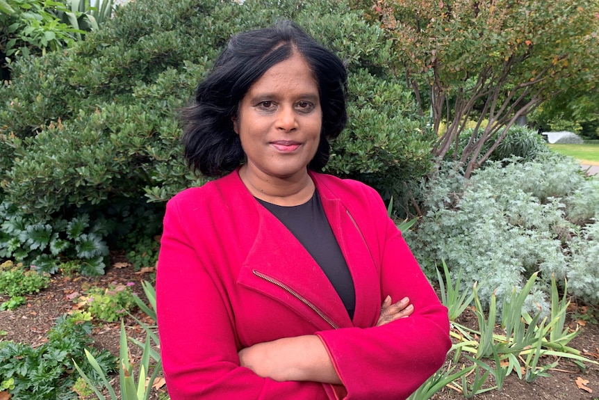 Farah wearing a red blazer with her arms folded.