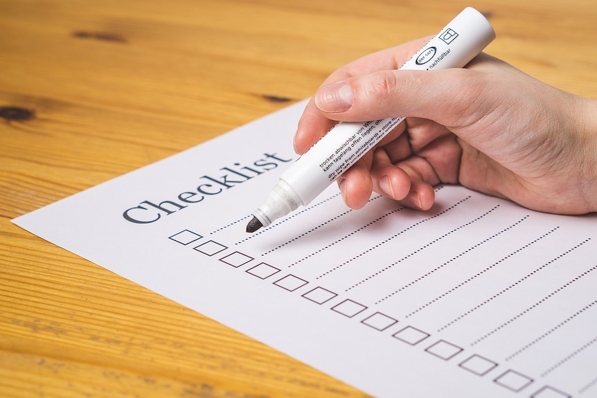 A checklist and a hand holding a marker