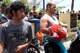 An unidentified survivor carrying a child at a marine police station on the coast of Pangandaran.