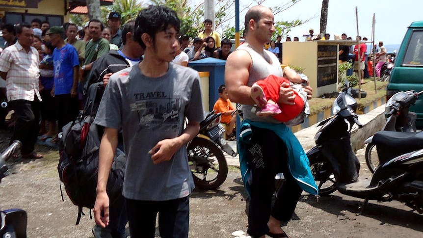 An unidentified survivor carrying a child at a marine police station on the coast of Pangandaran.