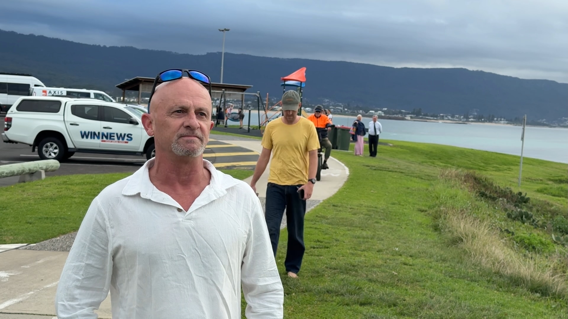 A man in a white shirt with the beach in the background