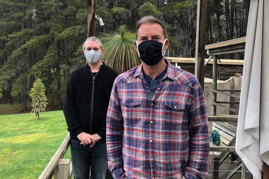 two men stand wearing masks